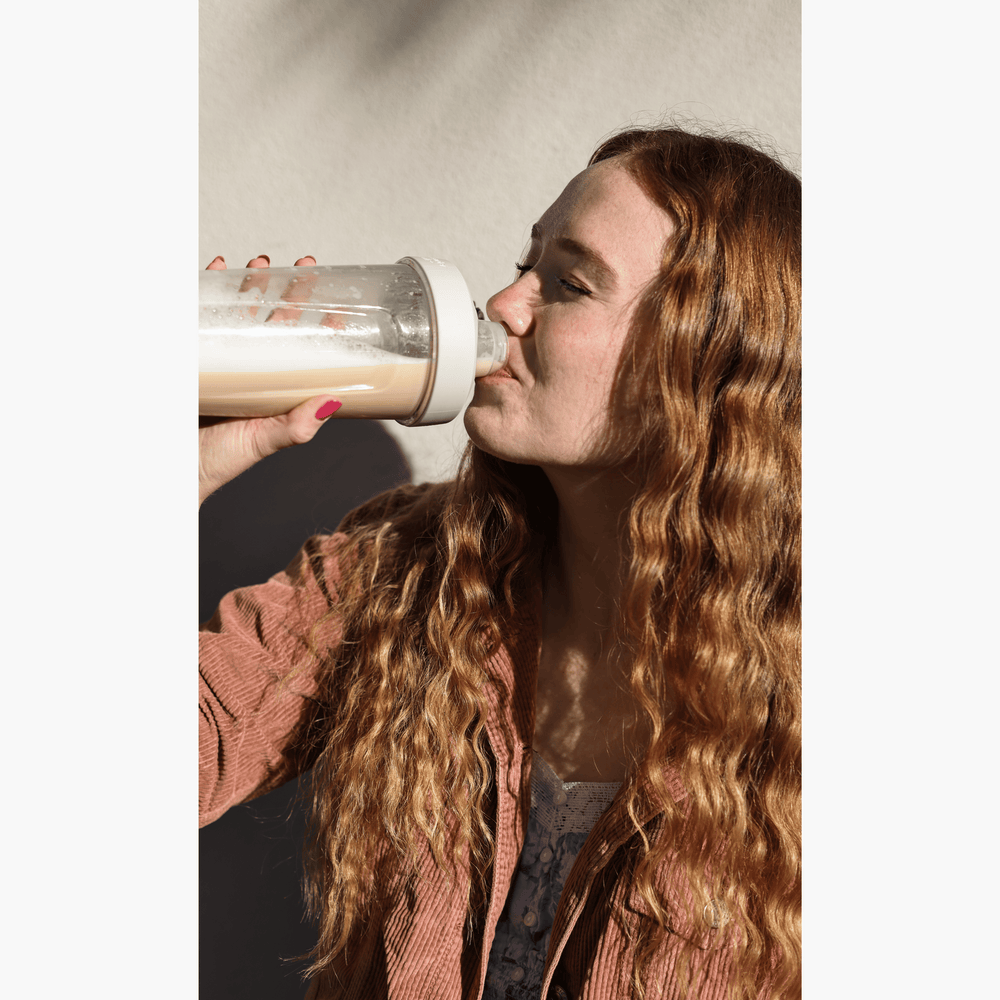 Attractive woman with red hair drinking a meal replacement shake